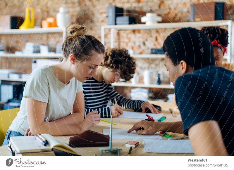 Junge Menschen sitzen zusammen am Tisch und unterhalten sich Leute People Person Personen erwachsen Erwachsene Männer männlich jung junge Männer Millennial