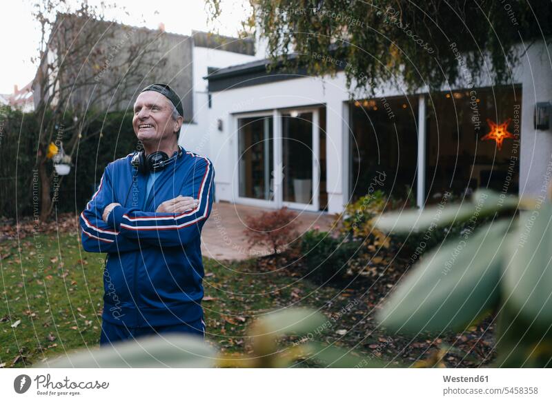 Fröhlicher sportlicher älterer Mann im Trainingsanzug im Garten stehend innere Haltung Einstellung Geisteshaltung innere Einstellung Schirmmütze Mütze