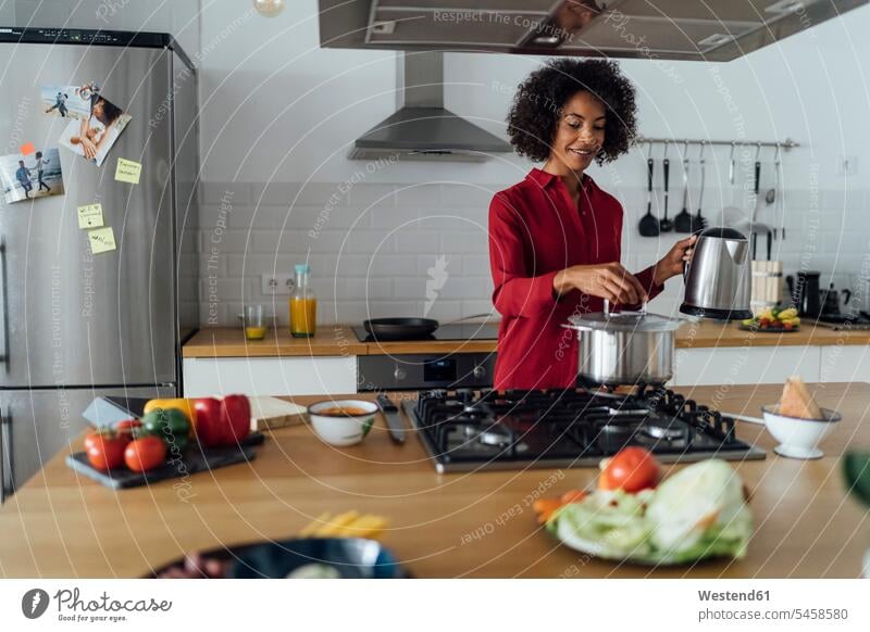 Frau steht in der Küche und bereitet Essen vor Afroeuropäer Afro-Europäer Afroeuropäisch Afro-Europäisch zubereiten kochen Essen zubereiten schwarzhaarig