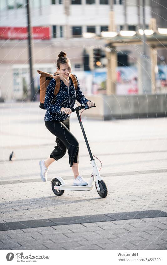 Junge Frau fährt Elektroroller in der Stadt Leute Menschen People Person Personen Europäisch Kaukasier kaukasisch 1 Ein ein Mensch eine nur eine Person single