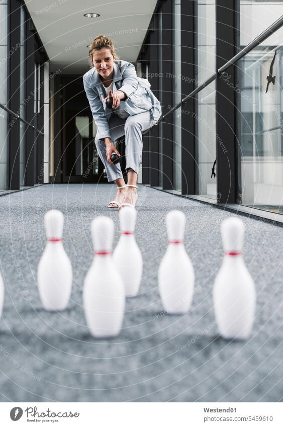 Lächelnder Geschäftsmann beim Kegeln in Bürodurchgang Office Büros Gang Bowling bowlen lächeln Geschäftsfrau Geschäftsfrauen Businesswomen Businessfrauen