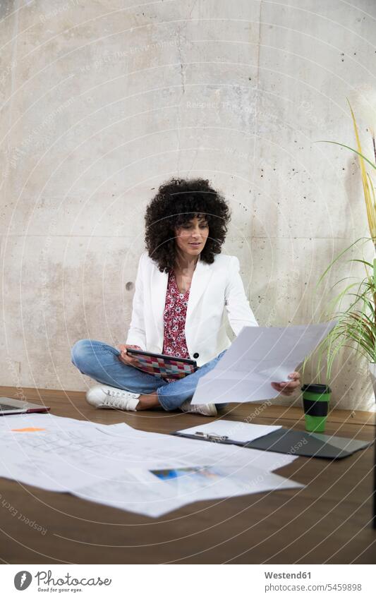 Geschäftsfrau sitzt auf dem Boden in einem Loft arbeiten mit Tablet und Dokumente Unterlagen Geschäftsfrauen Businesswomen Businessfrauen Businesswoman Lofts