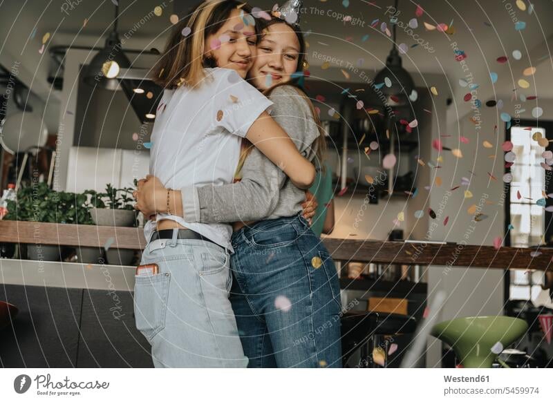 Liebevolle Teenager-Freunde umarmen sich, während sie zu Hause in der Geburtstagsfeier stehen Farbaufnahme Farbe Farbfoto Farbphoto Deutschland Innenaufnahme