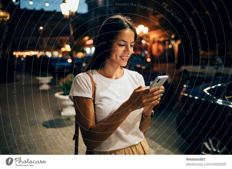 Junge Frau benutzt nachts in der Stadt ein Smartphone Informationen Telekommunikation telefonieren Handies Handys Mobiltelefon Mobiltelefone Lektüre Anruf