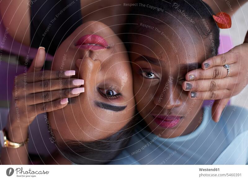 Porträt von zwei jungen Frauen Kopf an Kopf, die mit den Händen die Augen bedecken Leute Menschen People Person Personen Afrikanisch Afrikanische Abstammung