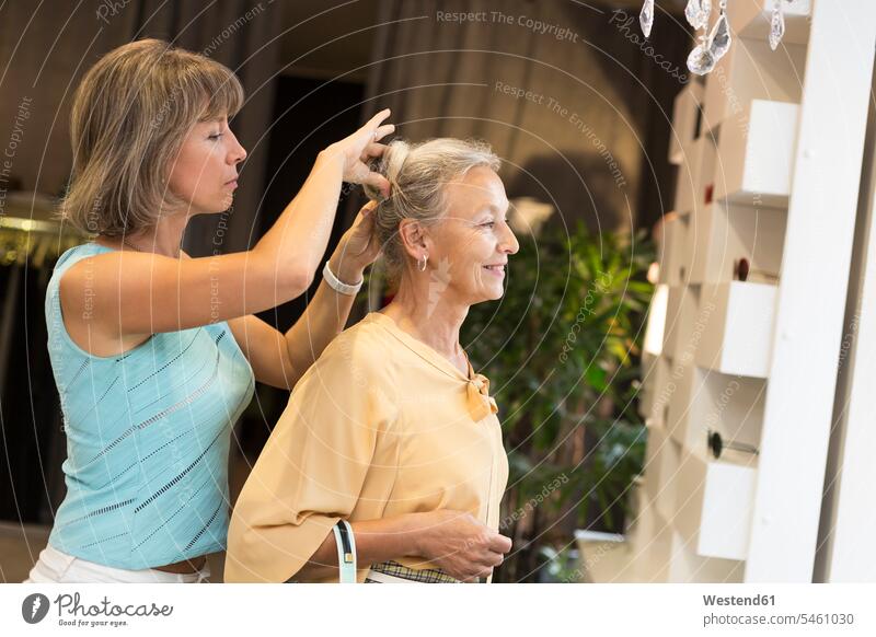 Frau hilft älteren Frau mit ihrem Haar in einem Geschäft Seniorin Seniorinnen alt Haare helfen mithelfen Hilfsbereitschaft beistehen Mithilfe Beistand Hilfe