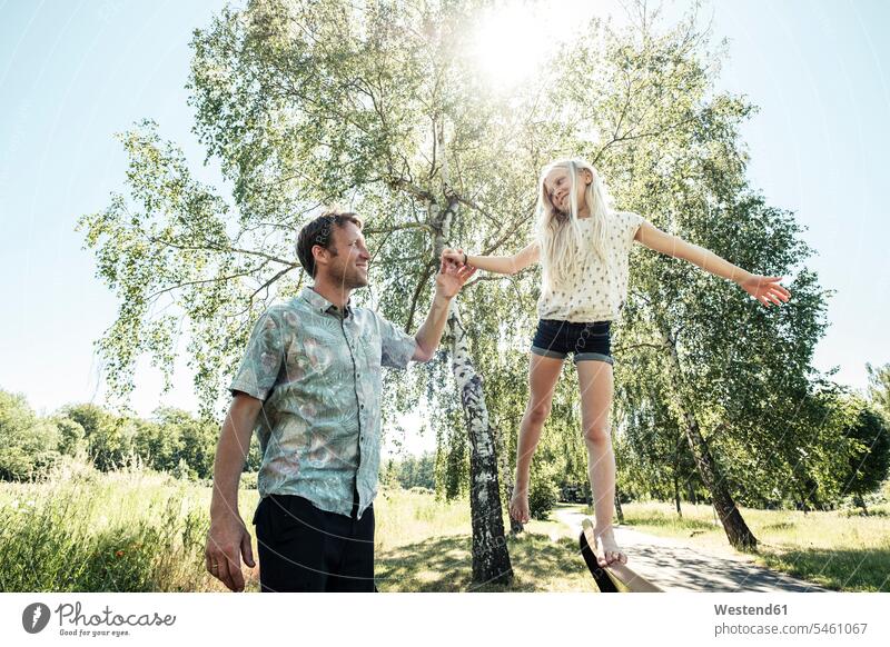 Vater hilft Tochter beim Balancieren auf einer Parkbank ausgeglichen Ausgeglichenheit Gleichgewicht Balance Jahreszeiten Frühjahr Lenz sommerlich Sommerzeit