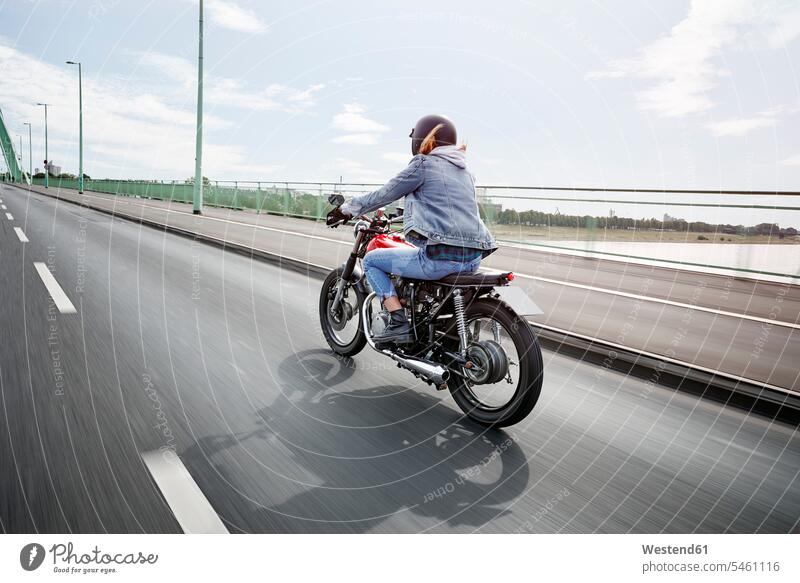 Junge Frau fährt Motorrad auf Brücke Motorräder fahren fahrend fahrender fahrendes weiblich Frauen Bruecken Brücken Kraftfahrzeug Verkehrsmittel KFZ