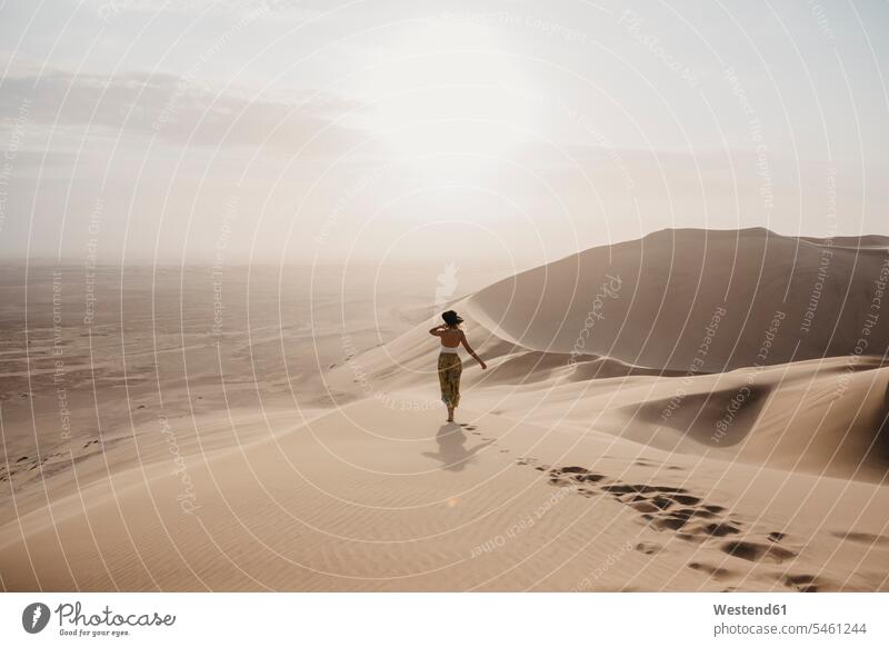 Namibia, Namib, Rückenansicht einer Frau, die auf einer Wüstendüne steht und auf die Aussicht schaut weiblich Frauen Wüstendünen Wuestenduene Wuestenduenen Düne