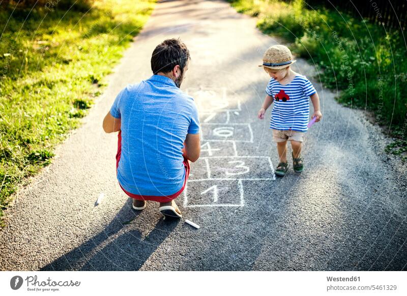 Vater spielt hopscotch zusammen mit seinem kleinen Sohn Söhne Papas Väter Vati Vatis Papis spielen Hüpfspiel Gemeinsam Zusammen Miteinander Kind Kinder Familie