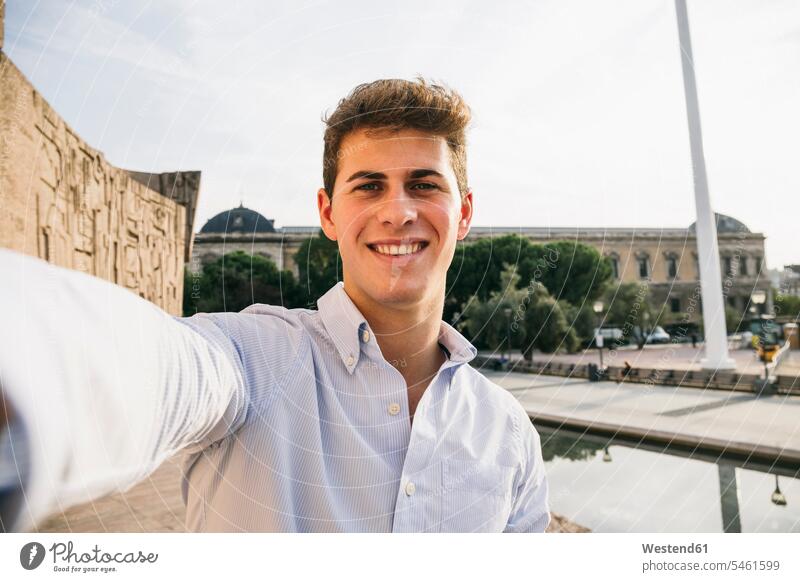 Lächelnder, gutaussehender junger Mann, der sich in der Stadt vor klarem Himmel in Selbstgefälligkeit übt Farbaufnahme Farbe Farbfoto Farbphoto Spanien