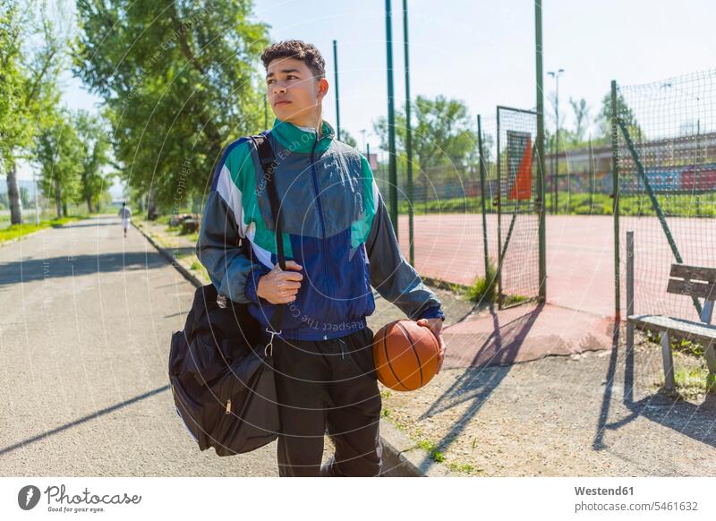 Junger Mann mit Basketball am Basketballplatz gemischtrassige Person Sport Tag am Tag Tageslichtaufnahme tagsueber Tagesaufnahmen Tageslichtaufnahmen tagsüber