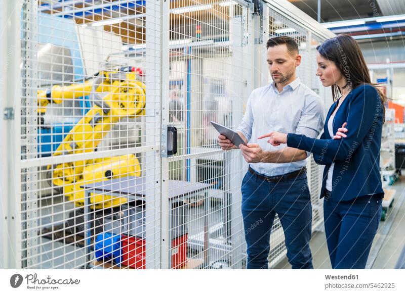 Geschäftsmann und Geschäftsfrau mit Tablet im Gespräch in der modernen Fabrik sprechen reden Businessmann Businessmänner Geschäftsmänner Fabriken