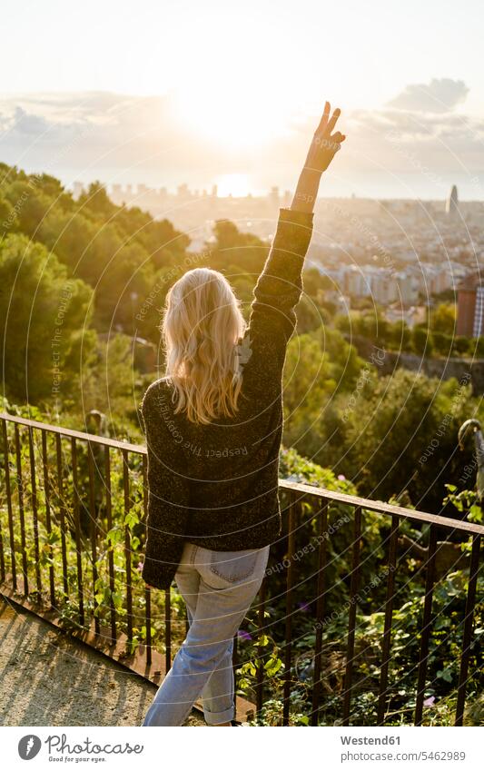 Rückansicht einer sorglosen jungen Frau, die bei Sonnenaufgang über der Stadt steht, Barcelona, Spanien Leute Menschen People Person Personen Europäisch