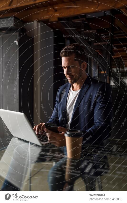 Selbstbewusster Geschäftsmann mit Handy und Laptop in einem Studio-Loft Zuversicht Zuversichtlich Selbstvertrauen selbstbewusst Vertrauen Atelier Studios