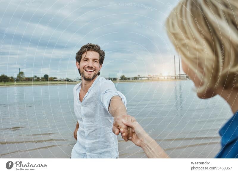 Deutschland, Düsseldorf, glückliches junges Paar am Rheinufer Glück glücklich sein glücklichsein Flussufer Pärchen Paare Partnerschaft Fluesse Fluß Flüsse Ufer