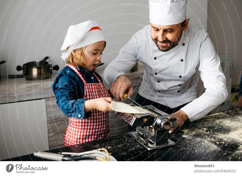 Vater und Tochter machen hausgemachte Nudeln mit der Nudelmaschine in der heimischen Küche Gastronomie Koeche Kuechenchef Kuechenchefs Köche Küchenchef