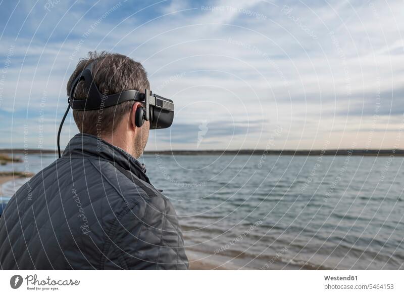 Mann mit VR-Brille am Seeufer Brillen Seen Männer männlich Virtuelle Realität Virtuelle Realitaet Gewässer Wasser Ufer Erwachsener erwachsen Mensch Menschen