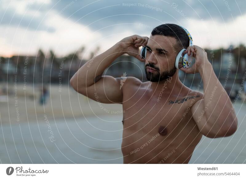 Porträt des barbusigen muskulösen Mannes mit Kopfhörern im Freien Portrait Porträts Portraits Männer männlich Muskeln athletisch Kopfhoerer Erwachsener
