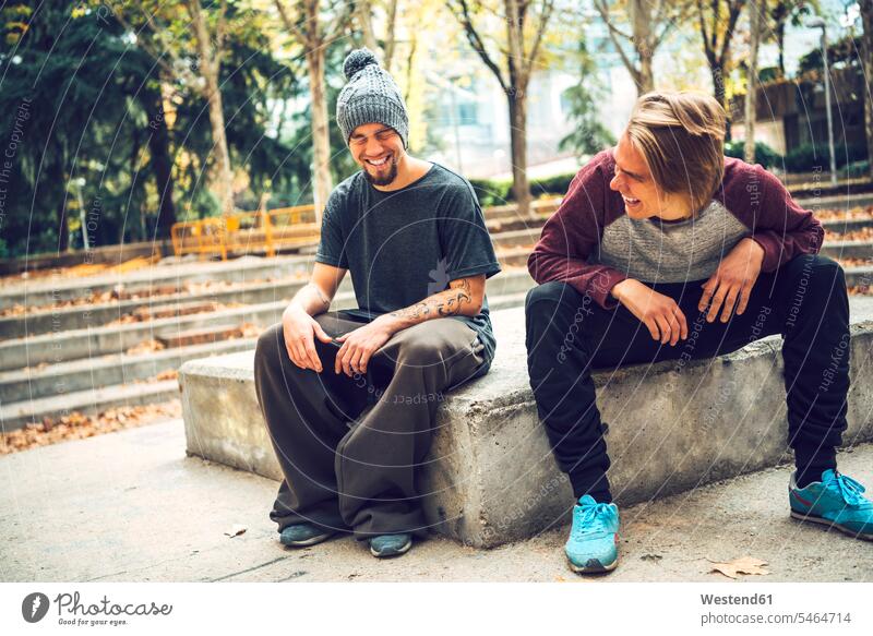 Fröhliche männliche Freunde genießen es, im Park zu sitzen Freizeitkleidung Freizeitbekleidung casual Farbaufnahme Farbe Farbfoto Farbphoto Tag