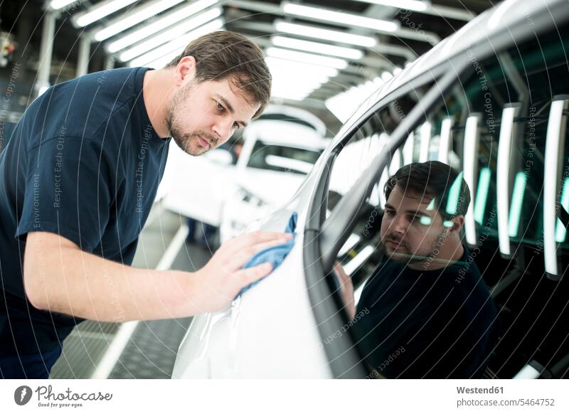 Mann arbeitet in moderner Autofabrik und wischt fertige Autos Job Berufe Berufstätigkeit Beschäftigung Jobs Arbeiter T-Shirts KFZ Verkehrsmittel Automobil PKW