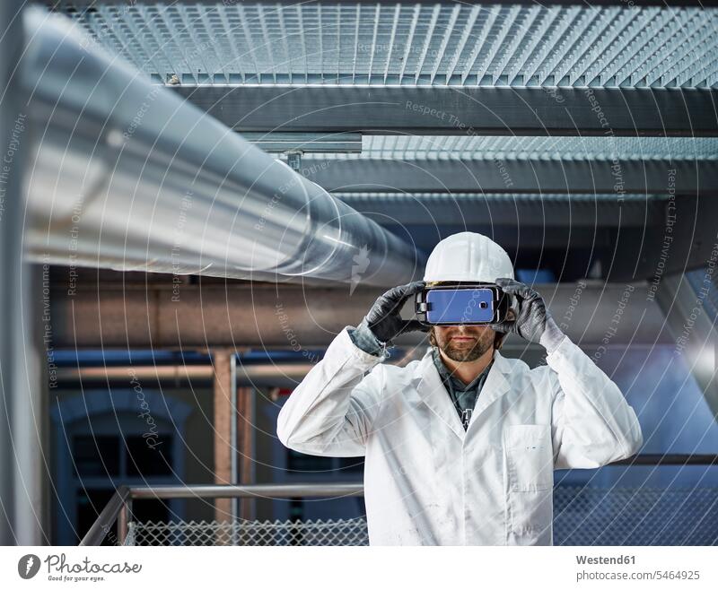 Techniker mit Schutzhelm, der durch eine VR-Brille schaut Virtual Reality Brille Virtual-Reality-Brille Virtual Reality-Brille VR Brille Rohrleitung