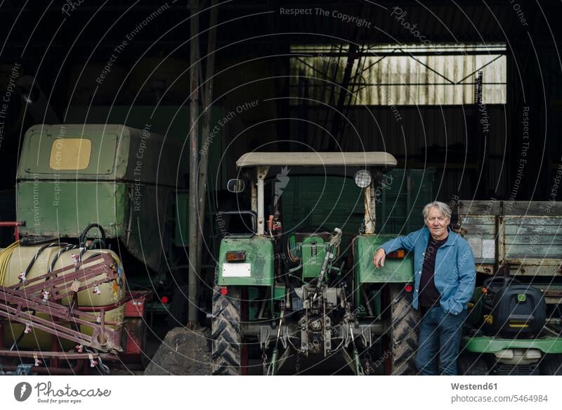 Porträt eines selbstbewussten älteren Mannes auf einem Bauernhof mit Traktor in der Scheune Landwirt Landwirte Hemden KFZ Verkehrsmittel Schlepper Traktoren