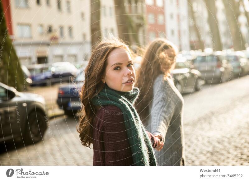 Porträt einer Teenagerin, die Hand in Hand mit ihrer besten Freundin auf der Straße geht Strassen Straßen junges Mädchen Teenagerinnen weiblich junge Frau