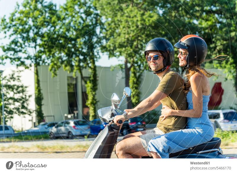 Glückliches Paar fährt Motorroller im Sommer Sommerzeit sommerlich Roller Piaggio Pärchen Paare Partnerschaft fahren glücklich glücklich sein glücklichsein