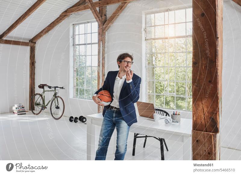 Geschäftsmann mit Basketball mit Smartphone im Penthouse Handy Mobiltelefon Handies Handys Mobiltelefone Businessmann Businessmänner Geschäftsmänner