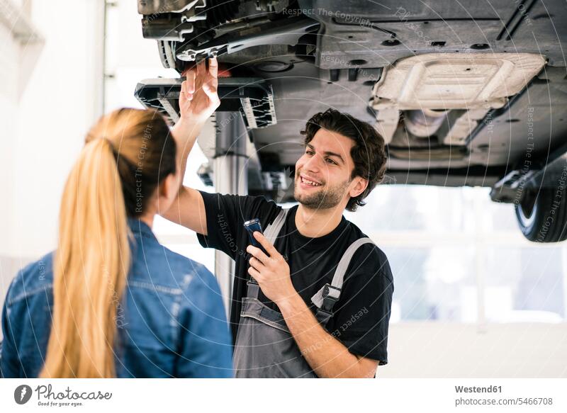 Automechaniker im Gespräch mit Kunden in der Werkstatt Job Berufe Berufstätigkeit Beschäftigung Jobs Gewerbe industriell Industrien Monteur KFZ Verkehrsmittel