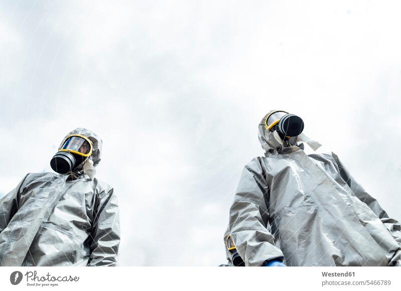 Niedrigwinkelansicht von Desinfektionsmitarbeitern in Schutzanzügen in der Stadt gegen den Himmel Farbaufnahme Farbe Farbfoto Farbphoto Coronavirus Covid-19