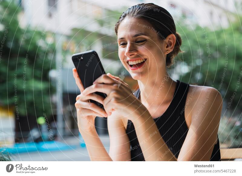 Junge Frau sitzt im Kaffeeladen und benutzt ein Smartphone Geschäftsfrau Geschäftsfrauen Businesswomen Businessfrauen Businesswoman lachen Cafe Kaffeehaus