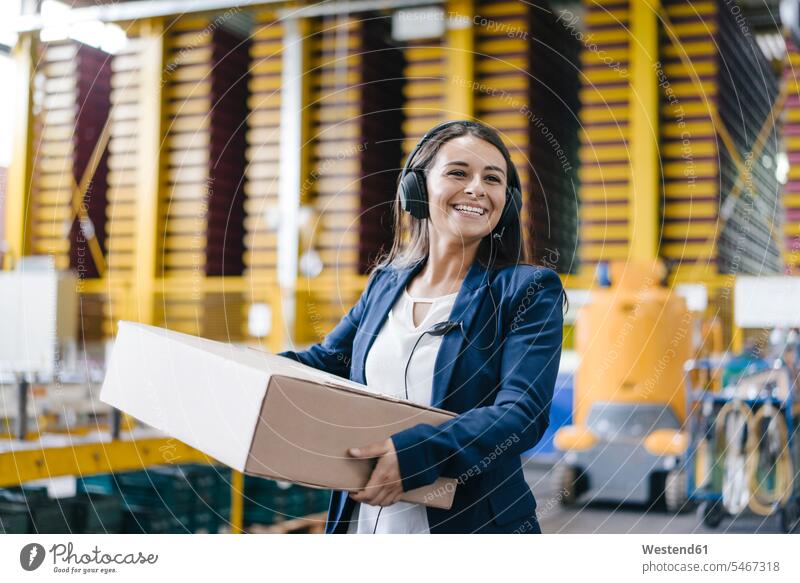 Junge Frau arbeitet beim Paketdienst, trägt Paket im Lager Angestellte tragen Unternehmen Logistikunternehmen Dienstleistung Angestellter Arbeit Deutschland