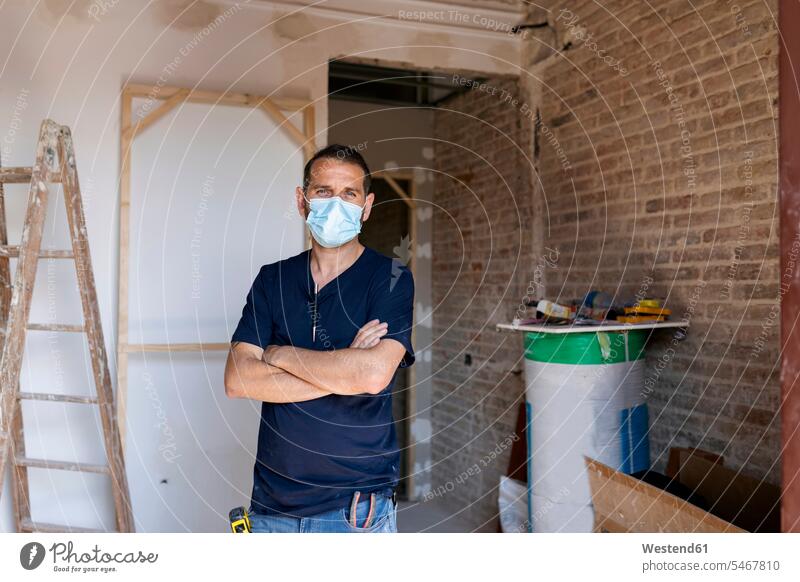 Porträt eines Mannes mit Schutzmaske in einem im Bau befindlichen Haus Job Berufe Berufstätigkeit Beschäftigung Jobs Arbeiter T-Shirts Renovierung stehend steht