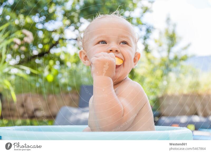 Junge sitzt in Baby-Badewanne und essen Obst männliche Babys männliches Baby männliche Babies sitzen sitzend niedlich süss süß putzig Badeeimer baden Kind
