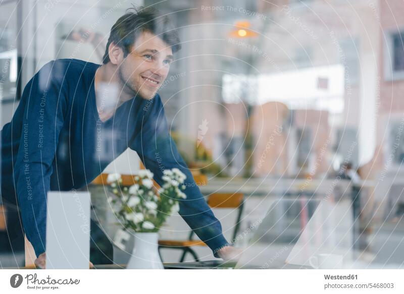 Lächelnder Mann in einem Cafe, der aus dem Fenster schaut Kaffeehaus Bistro Cafes Café Cafés Kaffeehäuser Männer männlich lächeln schauen sehend Gastronomie