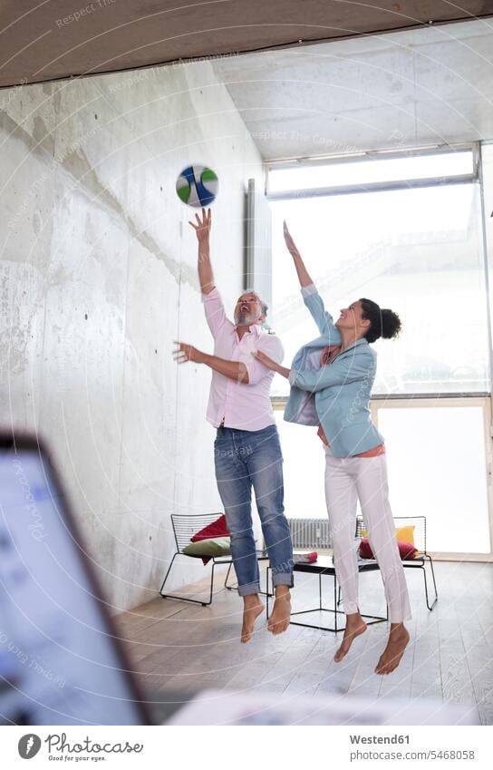 Lässiger Geschäftsmann und Geschäftsfrau spielen Basketball in einem Loft Businessmann Businessmänner Geschäftsmänner Lofts Basketbaelle Basketbälle