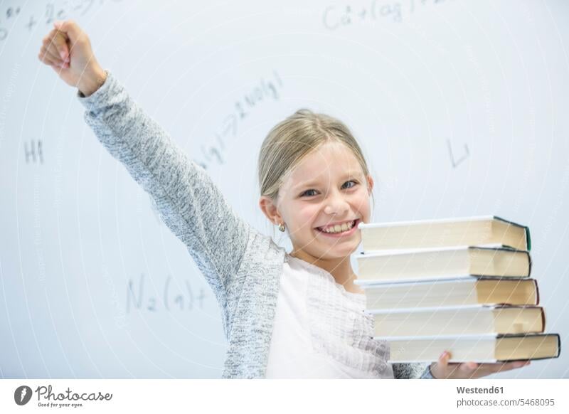 Porträt eines glücklichen Schulmädchens, das Bücher in der Klasse trägt Portrait Schulklasse Schule Schülerin Buch tragen Glück Schulkind Bildung positiv