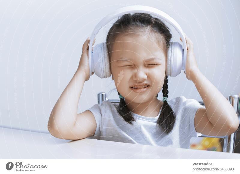Porträt eines kleinen Mädchens, das mit weißen schnurlosen Kopfhörern Musik hört Portrait Porträts Portraits weißes weißer weiss Kopfhoerer hören hoeren