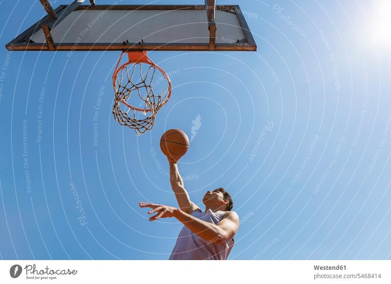 Junger Mann wirft den Basketball wolkenlos ohne Wolken Textfreiraum springen hüpfen Motivation Ansporn motiviert Antrieb motivieren Anreiz Agil Gewandtheit