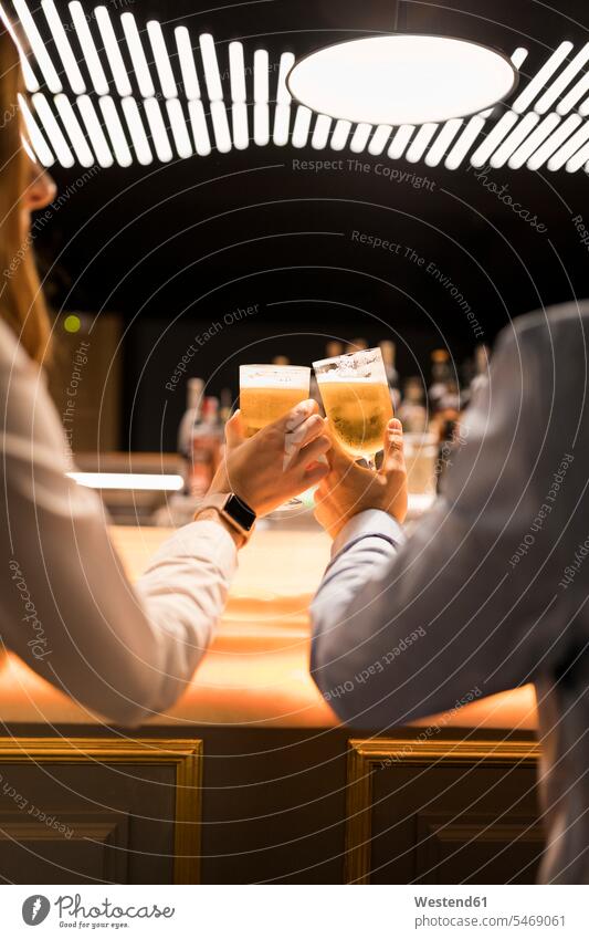 Nahaufnahme von Paar klirren Biergläser in einer Bar Bierglas anstoßen zuprosten anstossen Bars Pärchen Paare Partnerschaft Glas Trinkgläser Gläser Trinkglas