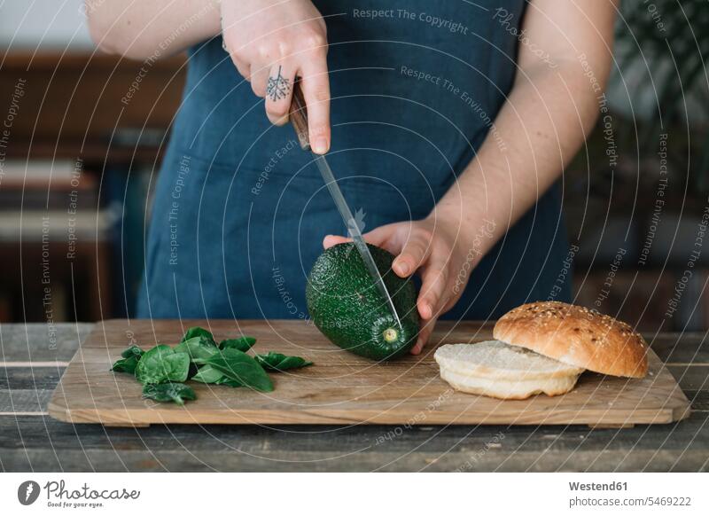 Frau bereitet veganen Burger zu, schneidet Avocado in Scheiben backen kochen vegetarisch Vegetarische Nahrung Vegetarische Ernährung Vegetarische Ernaehrung