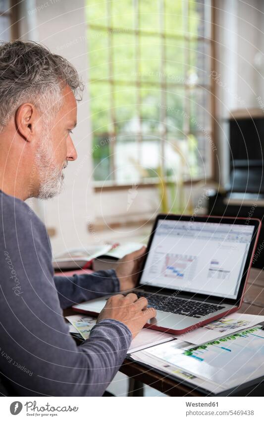 Reifer Mann arbeitet in seinem Heimbüro in einer Loft-Wohnung Lofts Home Office homeoffice zuhause zuhause arbeiten arbeiten von zuhause Laptop Notebook Laptops