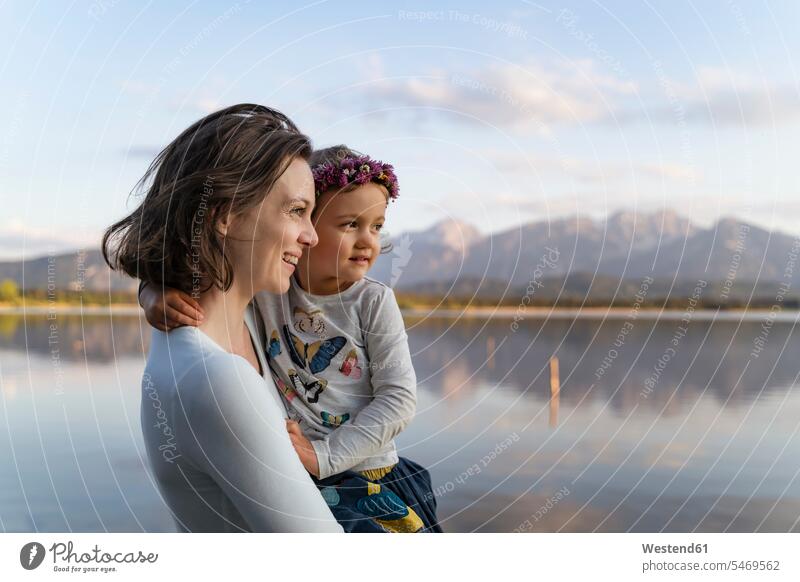Lächelnde Mutter mit niedlicher Tochter, die bei Sonnenuntergang am See steht Farbaufnahme Farbe Farbfoto Farbphoto Deutschland Freizeitbeschäftigung Muße Zeit
