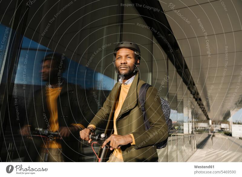 Porträt eines stilvollen Mannes mit Helm und Roller in der Stadt geschäftlich Geschäftsleben Geschäftswelt Geschäftsperson Geschäftspersonen Businessmann