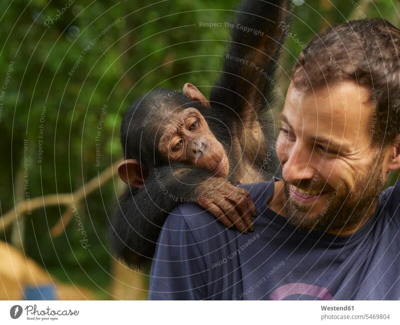 Kamerun, Pongo-Songo, Lächelnder Mann mit Schimpanse (Pan troglodytes) auf dem Rücken Zentralafrika Afrika Außenaufnahme außen draußen im Freien Tag