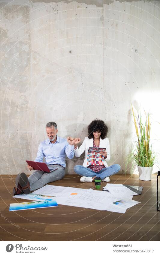 Geschäftsmann und Geschäftsfrau sitzen auf dem Boden in einem Loft mit Laptop und Tablet Geschäftsfrauen Businesswomen Businessfrauen Businesswoman Notebook