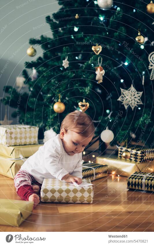 Baby Mädchen sitzt auf dem Boden Auspacken Weihnachtsgeschenke Fußboden Fußboeden Fussboeden Fussboden Fußböden Fussböden auspacken weibliche Babys