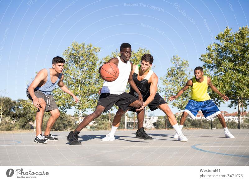 Junge Männer spielen Basketball und dribbeln den Ball auf dem Sportplatz Mannschaften Team Teams Bälle Muße Miteinander Zusammen trainieren Konkurrenz Wettkampf
